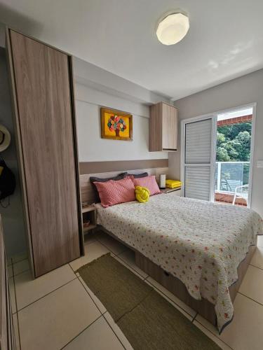 una camera da letto con un letto con cuscini rosa e una finestra di bwelcome - Apt with lovely view a Bertioga