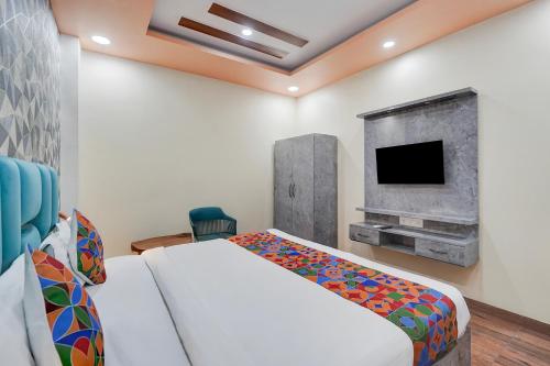 een slaapkamer met een wit bed en een tv bij FabHotel Raas Plaza in Kaliānpur
