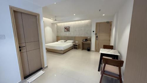 a bedroom with a bed and a table and a chair at Stae Residency Hitec City in Hyderabad