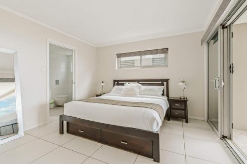 a white bedroom with a large bed and a window at Allure at Hyams Beach - seconds to white sands in Hyams Beach