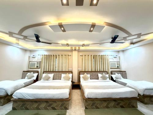 three beds in a room with a large ceiling at Hotel The Pushpraj in Varanasi