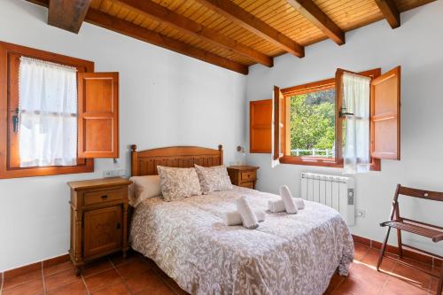 een slaapkamer met een bed en twee ramen bij La Llosona in Caño