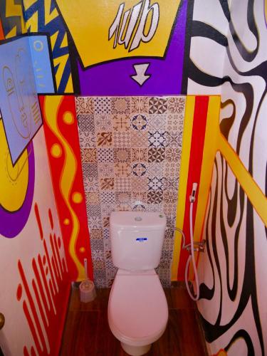 a bathroom with a toilet with graffiti on the wall at Azul Berg Hostel in Tamraght Ouzdar