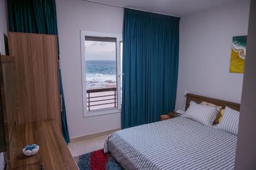a bedroom with a bed and a window with the ocean at Sea Front Zen Chalet Families Only in Marsa Matruh