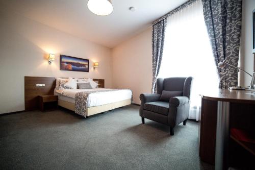 a hotel room with a bed and a chair at Hotel Sokołowska Airport Modlin in Nowy Dwór Mazowiecki