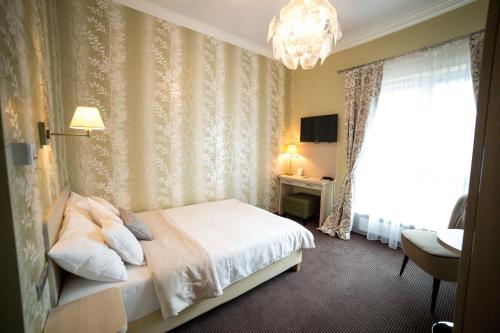 a hotel room with a bed and a chandelier at Hotel Sokołowska Airport Modlin in Nowy Dwór Mazowiecki
