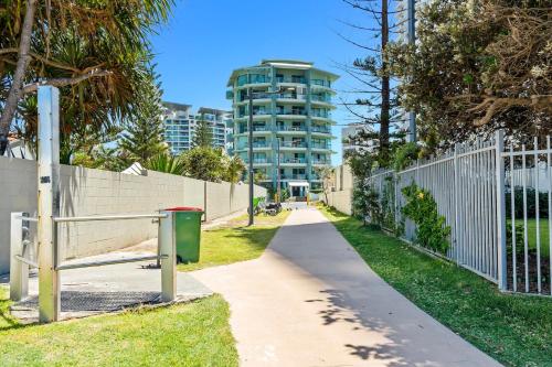 a walking path with a fence and a building at Emerald Sands Holiday Apartments in Gold Coast