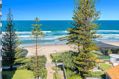 a view of a beach with two pine trees at Emerald Sands Holiday Apartments in Gold Coast