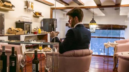 Ein Mann sitzt auf einem Stuhl an einem Tisch mit Weinflaschen. in der Unterkunft Hotel Catalina Suites in Valencia