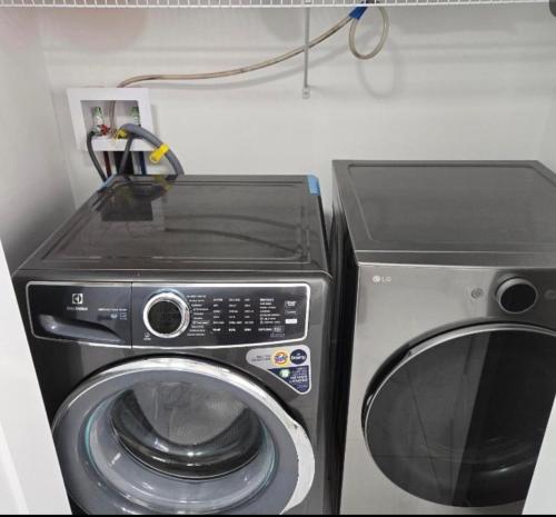 a microwave and a washing machine in a room at Platinum Homes , Stylish 3BR Home,4 Min to YQM Airport, Sleeps 10 Free Parking in Dieppe
