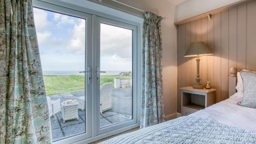 een slaapkamer met een bed en een glazen deur naar een balkon bij Hafan Nefyn in Nefyn