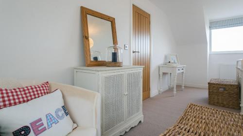 een woonkamer met een spiegel en een witte bank bij Hafan Nefyn in Nefyn