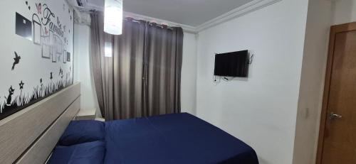a bedroom with a blue bed and a television at Apartamento próximo Aeroporto Cuiabá in Várzea Grande