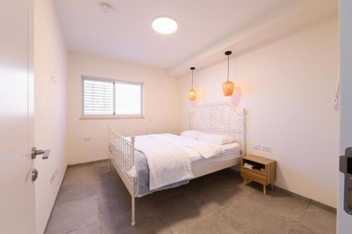 a white bedroom with a bed and a window at שלווה בנוף העמק in Gonen