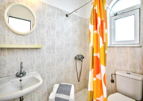 a bathroom with a sink and a toilet and a mirror at Paras Sun Hotel & Apartments in Ialysos
