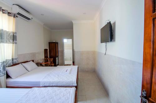 a bedroom with two beds and a tv on the wall at Kim Hồng Anh Guest House in Phu Quoc