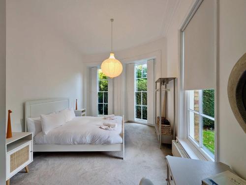 een slaapkamer met een wit bed en grote ramen bij Elegant 2-Bed Flat in Shenfield in Mountnessing