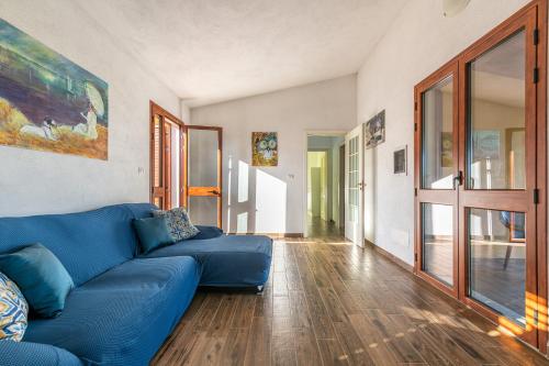 a blue couch in a living room with wooden floors at AffittaSardegna - Appartamenti Appentos in Capo Comino