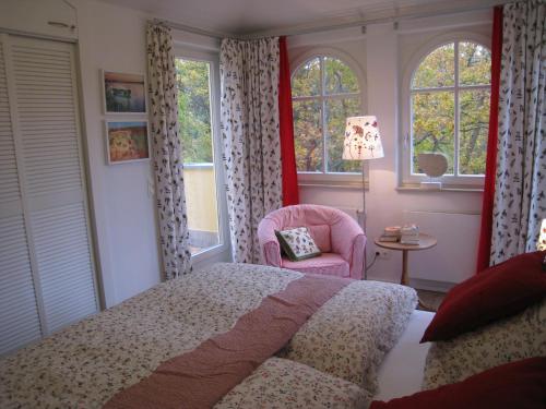 a bedroom with a bed and a chair and windows at Appartement Meeresrauschen in Baabe