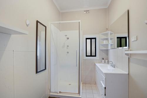 a white bathroom with a shower and a sink at Edwin Cottage Dubbo - close to the hospital in Dubbo