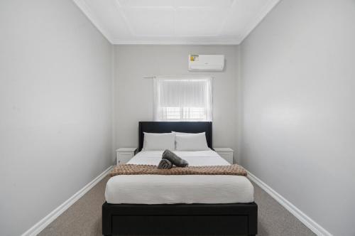 a bedroom with a bed in a white room at Edwin Cottage Dubbo - close to the hospital in Dubbo