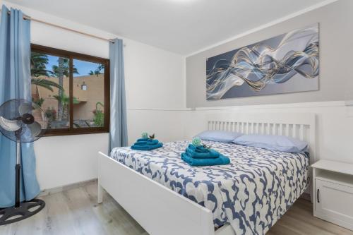 una camera da letto con un letto con asciugamani blu sopra di Horizon blu a Corralejo