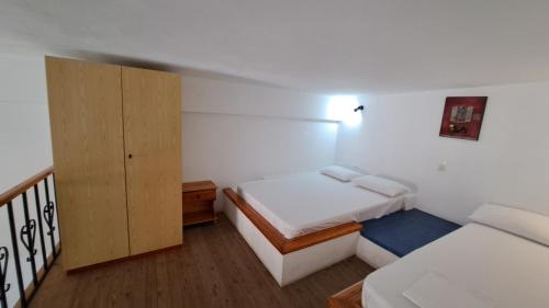 ein kleines Schlafzimmer mit 2 Betten und einem Schrank in der Unterkunft Artemis Studios in Agia Roúmeli