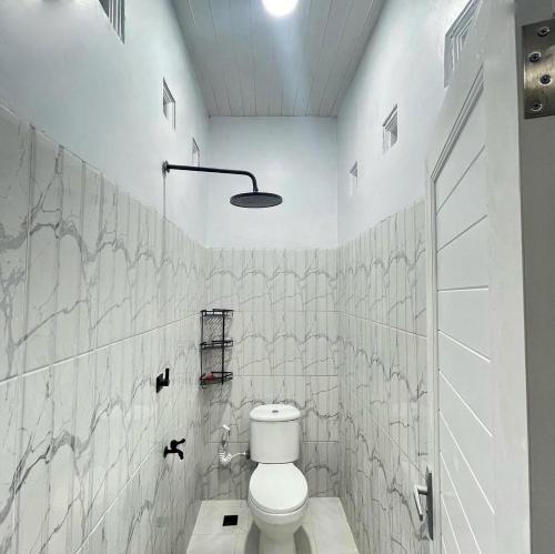 a white bathroom with a toilet and a shower at Utama Lueng Bata Hotel in Luengbata