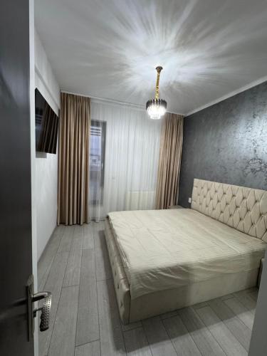 une chambre avec un grand lit et un lustre dans l'établissement Apartament Modern Penthouse Rm Valcea, à Valcea
