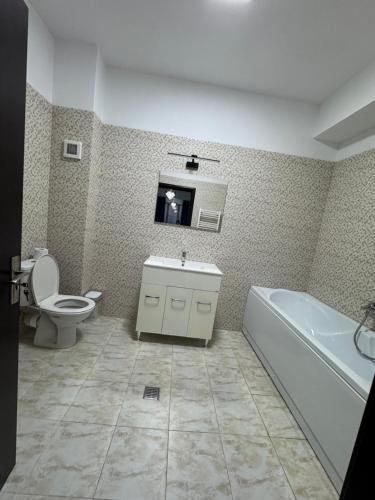 une salle de bains avec toilettes, baignoire et lavabo dans l'établissement Apartament Modern Penthouse Rm Valcea, à Valcea