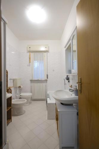 a white bathroom with two toilets and a sink at B&B L'uva Fragolina in Reggio Emilia