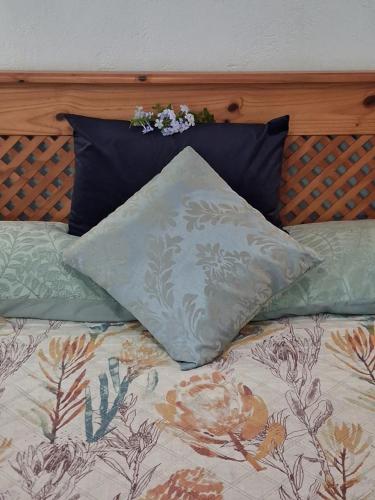 een bed met 2 kussens en een kussen erop bij Dombeya Ridge Guest Suite in Rustenburg