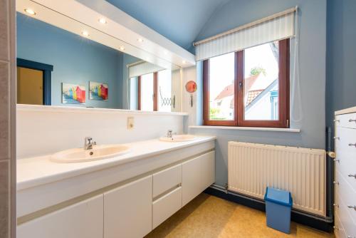 ein Badezimmer mit zwei Waschbecken und einem großen Spiegel in der Unterkunft Vakantiewoning Nungesser Coli in Koksijde