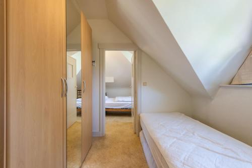 ein kleines Schlafzimmer im Dachgeschoss mit einem Bett und einer Treppe in der Unterkunft Vakantiewoning Nungesser Coli in Koksijde