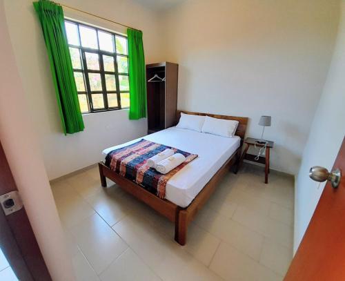 BUNGAVILLA House Tarapoto في تارابوتو: غرفة نوم بسرير ونافذة مع ستائر خضراء