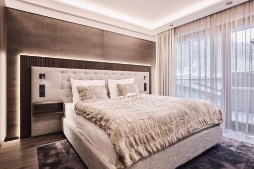 ein Schlafzimmer mit einem großen Bett und einem großen Fenster in der Unterkunft Chalet Ischgl - Modern Luxury Residences in Ischgl