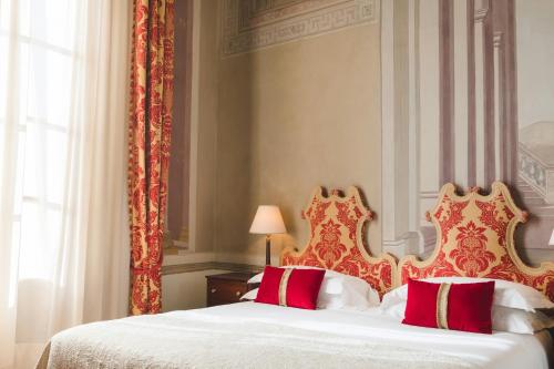 a bedroom with a bed with red and white pillows at Grand Hotel Continental Siena - Starhotels Collezione in Siena