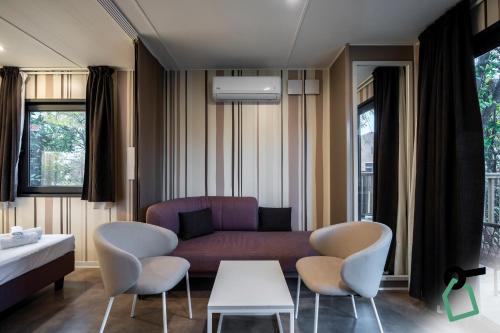 un soggiorno con un divano e delle sedie viola di Hotiday Bologna Arena a Bologna