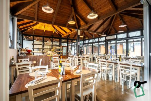 una sala da pranzo con tavoli in legno e sedie bianche di Hotiday Bologna Arena a Bologna