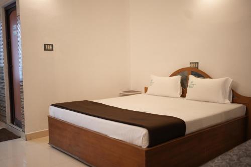 una camera da letto con un letto grande con testiera in legno di Thekkady Arasi Hotel a Thekkady