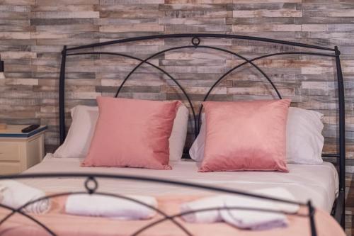 een bed met twee roze kussens voor een bakstenen muur bij Sassari Station Inn in Sassari