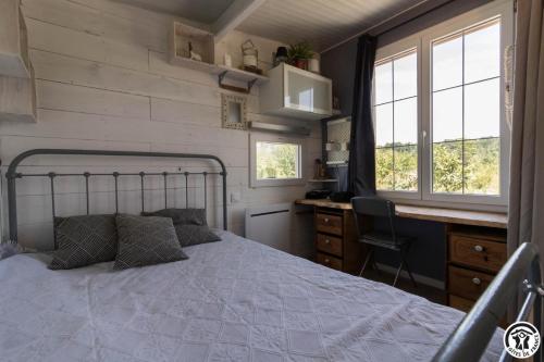a bedroom with a bed and a desk and windows at Le panier bio de noé in Noé
