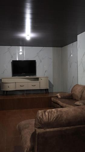 a living room with a flat screen tv and two couches at Honey Chalet in Al Khayyām