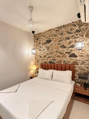 a bed in a room with a stone wall at Palm Breeze Hotel - Colaba in Mumbai