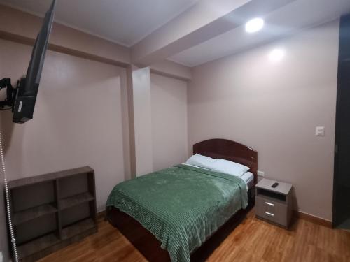 een slaapkamer met een bed met een groene deken bij Casa Sol in Tingo María