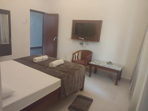 a room with two beds and a tv and a chair at Prestige Palace in Mugad