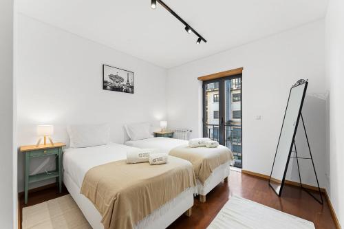 two beds in a white room with a window at GuestReady - Cosy Gaia Retreat in Vila Nova de Gaia