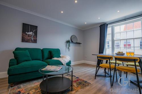 a living room with a green couch and a table at Guest Stays - Bridge Street Apartment in Evesham