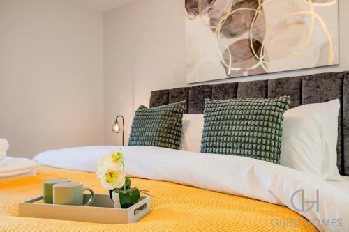 a bedroom with a bed with white sheets and green pillows at Guest Stays - Bridge Street Apartment in Evesham