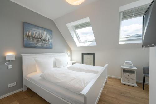 1 Schlafzimmer mit einem weißen Bett und 2 Fenstern in der Unterkunft Ferienhaus am See LEE - Vogteihof am Bodden in Streu